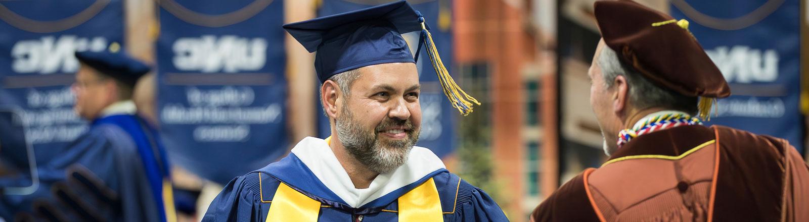 Male graduate student receiving congratulations at commencement ceremony.